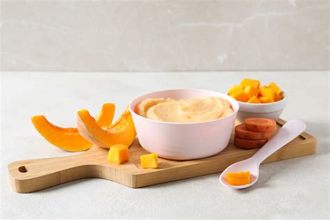 Un bebeluș fericit care mănâncă piure de dovleac dintr-un bol