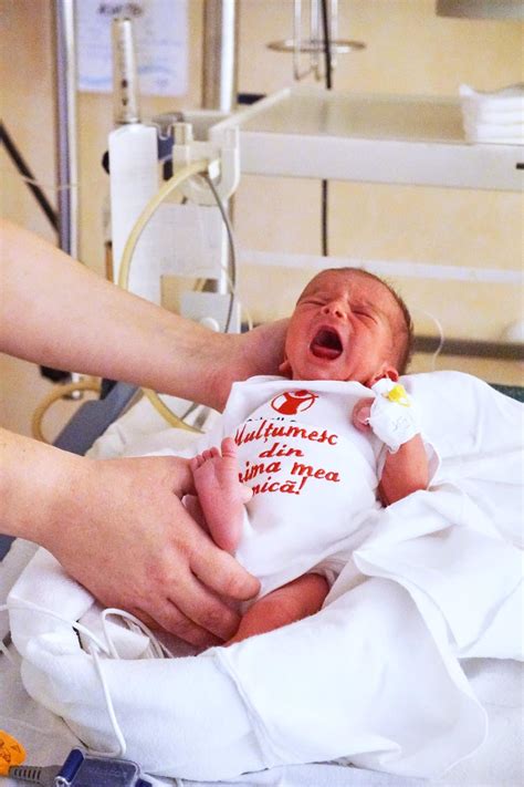 Fotografie cu un copil născut prematur, acum sănătos și fericit, alături de părinții săi, vizitând spitalul