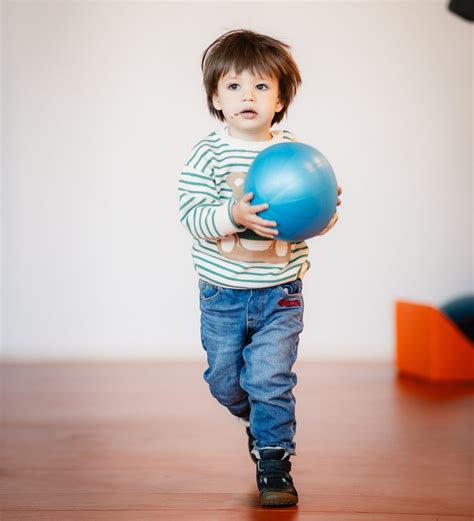 Copil aruncând o minge într-o cutie