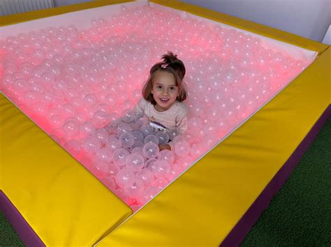 Copil într-o cameră senzorială cu mingi luminoase și texturi variate