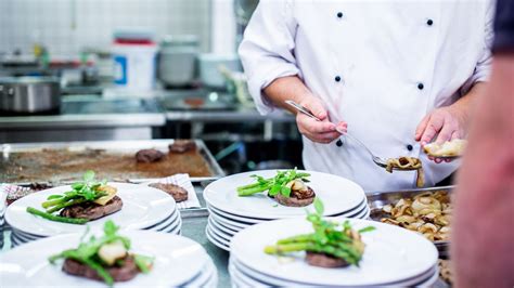 Ajutor de bucătar care aranjează preparatele pe farfurii