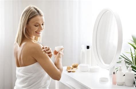 Femeie care aplică o cremă hidratantă pe sâni.