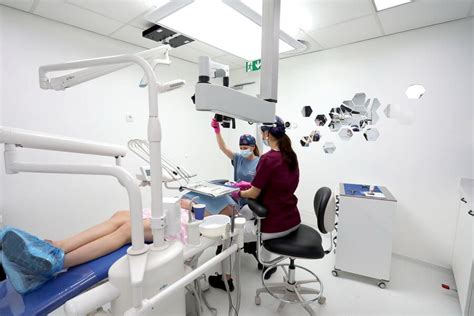 Imagine cu un medic dentist care efectuează un tratament de canal, purtând echipament de protecție