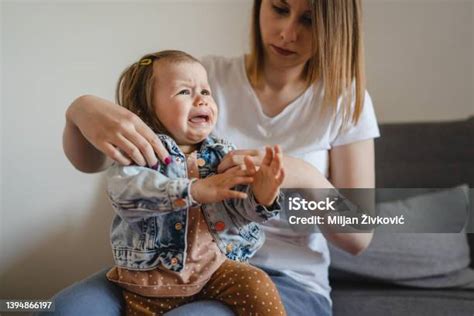 Copil mic plângând în brațele mamei