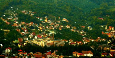 Peisaj pitoresc al stațiunii Băile Olănești, cu vegetație luxuriantă și clădiri în stil balnear.