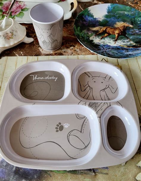 Colaj cu diverse produse din categoria veselă pentru copii: seturi de castroane, farfurii cu motive, tacâmuri ergonomice și cănuțe cu pai.