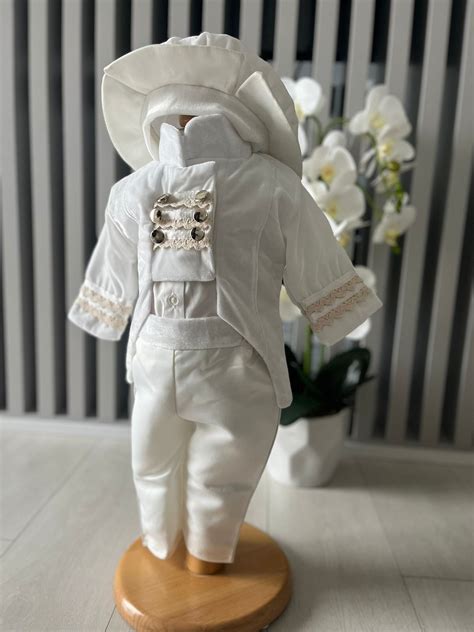 Set de hăinuțe albe pentru botez, cu detalii delicate.