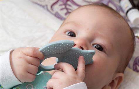 fotografie cu un bebeluș care folosește o jucărie de dentiție rece