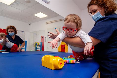 Copil practicând exerciții de kinetoterapie sub supravegherea unui terapeut