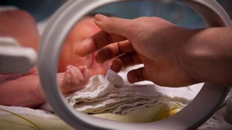 fotografie cu un bebeluș de 1 an care se ridică în picioare sprijinindu-se de mobilă