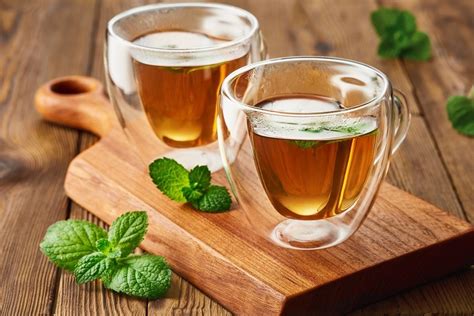 Ilustrație cu o sticlă de ceai de mentă și o pernă cu apă caldă pe abdomen