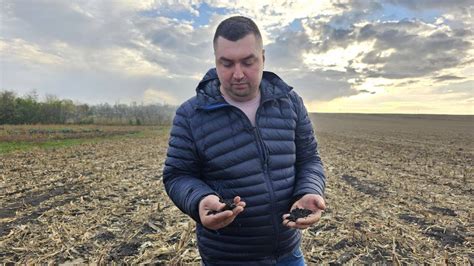 Imagine cu inginerul agronom Constantin Buliga ținând în mână sol negru, bogat.