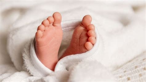 Bebeluș de 10 luni care se ridică în picioare sprijinindu-se de un obiect