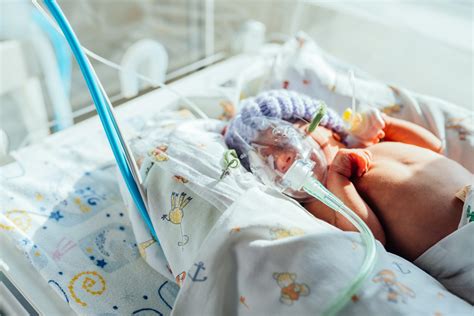 Imagine cu un medic neonatolog care examinează un bebeluș prematur în incubator