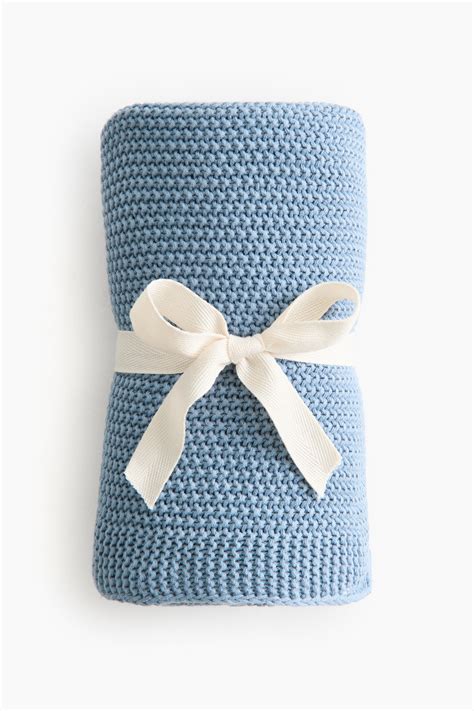 O păturică pentru bebeluși cu imprimeu subtil de frunze într-o nuanță de verde salvie