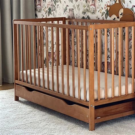 Ilustrație detaliată a unui patut din lemn, cu accent pe elementele de siguranță: balustrade, margini rotunjite, somieră reglabilă.