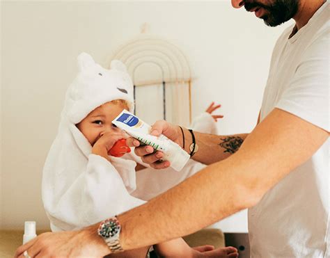 Ilustrație cu bebeluș aplicând cremă hidratantă Mustela pe piele.