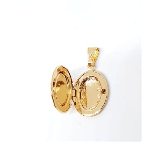 Fotografie de prim-plan a unui medalion din argint gravat cu un model specific pentru bebeluși, cum ar fi o inimioară sau o stea.