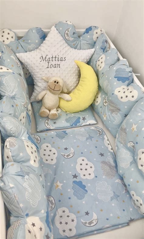 Ilustrație cu diverse piese ale unei lenjerii de pat pentru bebeluși: cearșaf, pilotă, pernă, păturică, apărători de pat