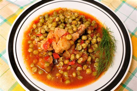 O farfurie cu mazăre, bucăți de carne de porc și morcovi baby, prezentată apetisant.