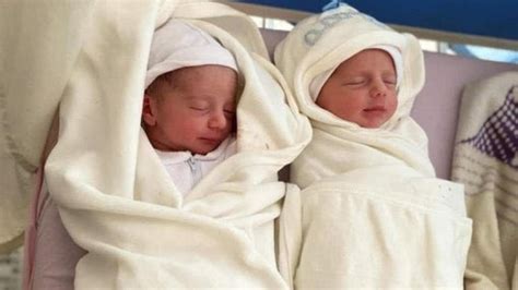 Ilustrație cu mama care îngrijește doi bebeluși gemeni, unul plângând, celălalt dormind.