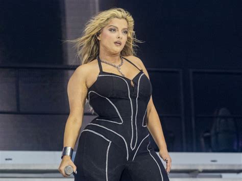 O fotografie a lui Bebe Rexha în timpul unui concert, cu o imagine care reflectă mesajul său de acceptare corporală.