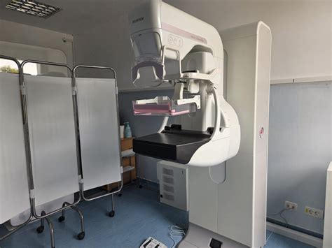 Ilustrație a interacțiunii dintre pacientă și asistenta medicală în timpul unei mamografii, accentuând suportul și confortul oferit.